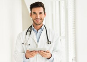 Médico sorridente com estetoscópio e tablet nas mãos, simbolizando confiança, autoridade e uso de tecnologia na prática clínica.