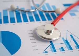 Estetoscópio sobre gráficos de desempenho com barras e pizza, representando a análise de resultados em estratégias de marketing médico.